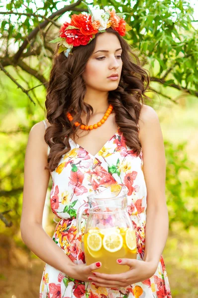 Menina bonita nova em uma grinalda de flores com limonada — Fotografia de Stock