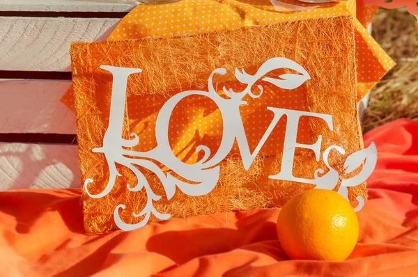 Dekorace slovo láska na oranžovém pozadí v létě — Stock fotografie