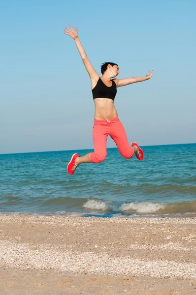 Jovem bela mulher atleta pulando na praia — Fotografia de Stock