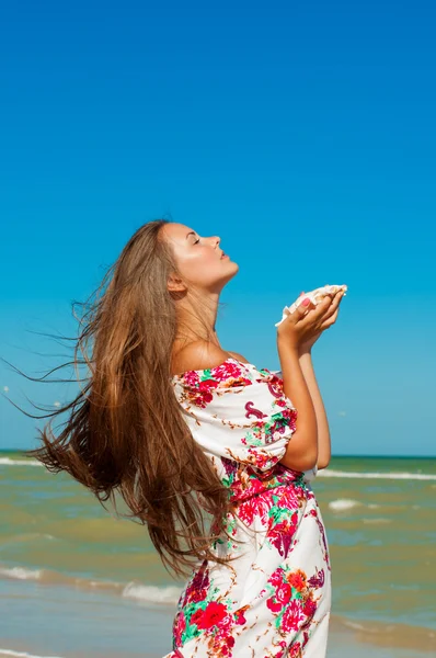 Hermosa chica con el pelo largo en la playa con concha — Foto de Stock