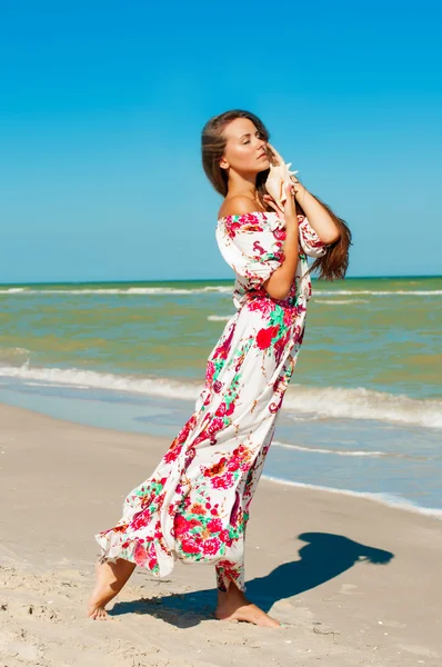 Schöne Mädchen mit langen Haaren am Strand mit Muschel — Stockfoto