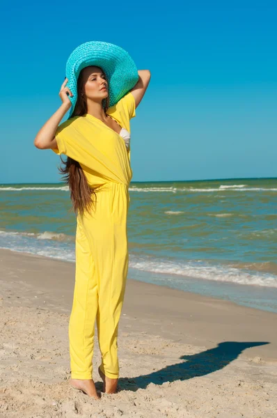 Vacker flicka med långt hår på stranden i en blå hatt — Stockfoto