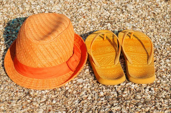 Světlé letní klobouk a sandály na pláži — Stock fotografie