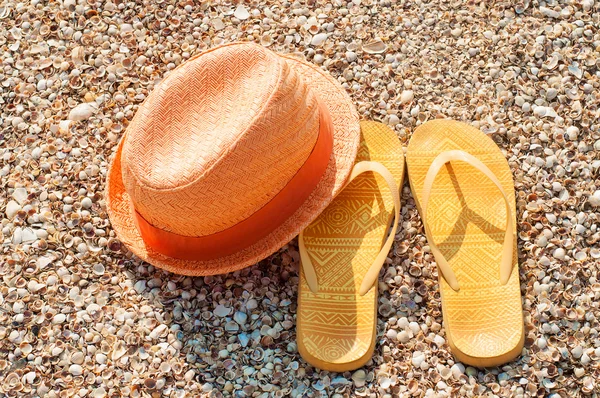 Světlé letní klobouk a sandály na pláži — Stock fotografie