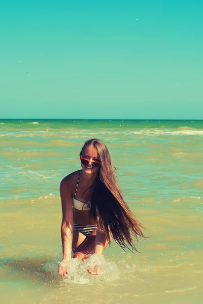 Chica joven en el agua de mar salpica y sonríe — Foto de Stock
