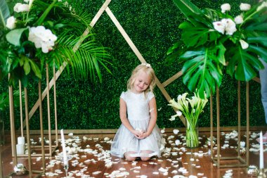  Beyaz elbiseli, sarı saçlı, beyaz çiçekli, nilüferli ve orkideli yeşil tropikal bitkileri olan tatlı bir kız.