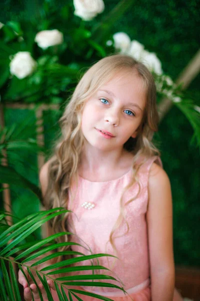 可爱的姑娘 金黄色的长发 穿着粉红色的衣服 百合花和兰花 背靠着绿色的热带植物 — 图库照片