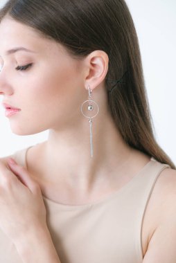 Uzun siyah saçlı, güzel bir kızda son moda gümüş küpeler. Güzellik ve moda 