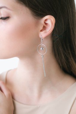 Uzun siyah saçlı, güzel bir kızda son moda gümüş küpeler. Güzellik ve moda 