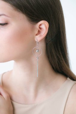 Uzun siyah saçlı, güzel bir kızda son moda gümüş küpeler. Güzellik ve moda 