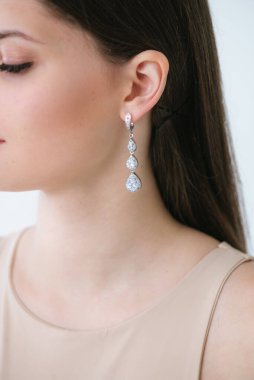 Uzun siyah saçlı, güzel bir kızda son moda gümüş küpeler. Güzellik ve moda 