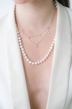 Beyaz ceketli, güzel bir genç kızın üzerinde inci kolye var. Güzellik ve moda 