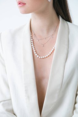 Beyaz ceketli, güzel bir genç kızın üzerinde inci kolye var. Güzellik ve moda 