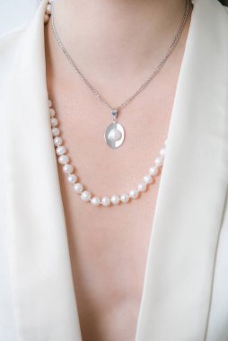 Beyaz ceketli, güzel bir genç kızın üzerinde inci kolye var. Güzellik ve moda 