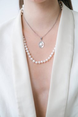 Beyaz ceketli, güzel bir genç kızın üzerinde inci kolye var. Güzellik ve moda 
