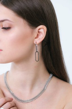 Uzun siyah saçlı, güzel bir kızda son moda gümüş küpeler. Güzellik ve moda 
