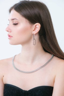 Uzun siyah saçlı güzel bir kızda moda gümüş küpeler ve kolye. Güzellik ve moda 