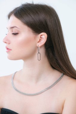 Uzun siyah saçlı güzel bir kızda moda gümüş küpeler ve kolye. Güzellik ve moda 