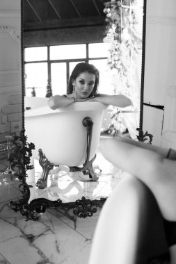 Siyah bikinili, siyah saçlı çekici bir genç kız büyük bir banyo aynasının yansımasında. Boş & Spa 