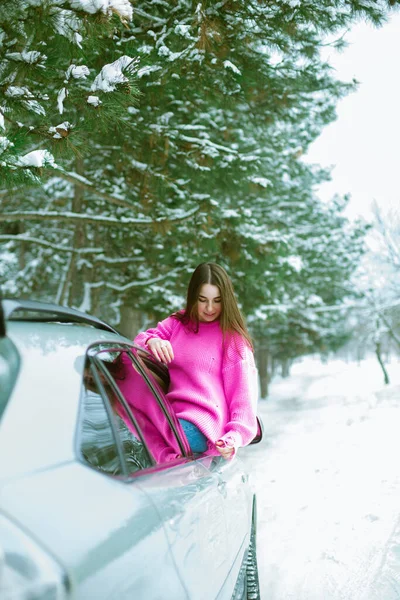 스웨터를 귀여운 소녀는 웃으며 내리는 길에서 자동차 내다본다 — 스톡 사진
