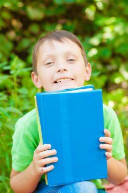 Cute boy in a green t-shirt with a school backpack and school books in the park. Back to school