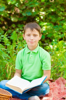 Cute boy in a green t-shirt with a school backpack and school books in the park. Back to school