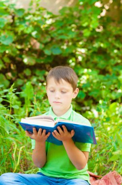 Cute boy in a green t-shirt with a school backpack and school books in the park. Back to school