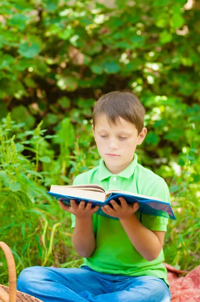 Cute boy in a green t-shirt with a school backpack and school books in the park. Back to school