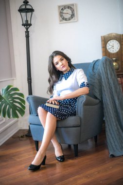 A cute teenage girl with long hair in a classic school dress in a classic interior with books and notebooks at the lesson. School life. Back to school