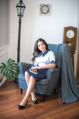 A cute teenage girl with long hair in a classic school dress in a classic interior with books and notebooks at the lesson. School life. Back to school