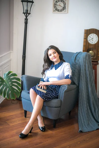 A cute teenage girl with long hair in a classic school dress in a classic interior with books and notebooks at the lesson. School life. Back to school