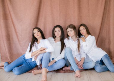 Stüdyoda modaya uygun kot ve beyaz gömlekli güzel genç kızlar var. Tekstil arka planında. Gençlik modası. güzellik ve moda