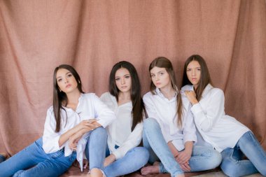 Stüdyoda modaya uygun kot ve beyaz gömlekli güzel genç kızlar var. Tekstil arka planında. Gençlik modası. güzellik ve moda