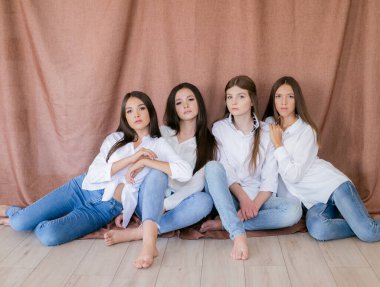 Stüdyoda modaya uygun kot ve beyaz gömlekli güzel genç kızlar var. Tekstil arka planında. Gençlik modası. güzellik ve moda