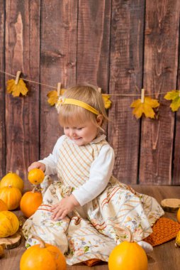 Little cute girl with orange pumpkins. Autumn mood. Halloween.