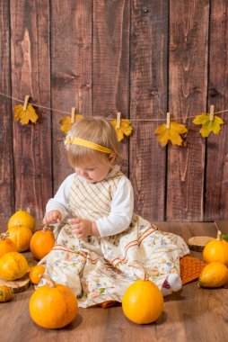 Little cute girl with orange pumpkins. Autumn mood. Halloween.
