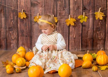 Little cute girl with orange pumpkins. Autumn mood. Halloween.