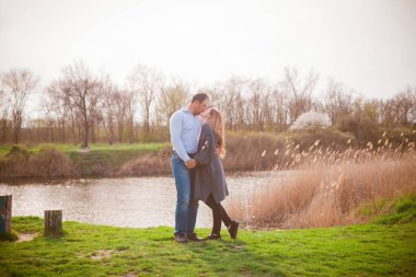 Bir çift uzun boylu genç adam ve uzun sarı saçlı kız arkadaşı nehir kıyısında şehrin dışında yürüyorlar. Duygular ve duygular. Yaşam tarzı. Ülke havası