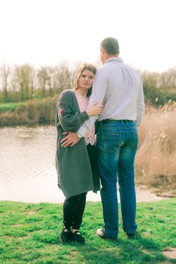 Bir çift uzun boylu genç adam ve uzun sarı saçlı kız arkadaşı nehir kıyısında şehrin dışında yürüyorlar. Duygular ve duygular. Yaşam tarzı. Ülke havası