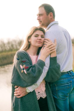 Bir çift uzun boylu genç adam ve uzun sarı saçlı kız arkadaşı nehir kıyısında şehrin dışında yürüyorlar. Duygular ve duygular. Yaşam tarzı. Ülke havası