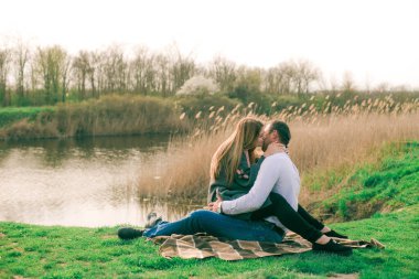 Bir çift uzun boylu genç adam ve uzun sarı saçlı kız arkadaşı nehir kıyısında şehrin dışında yürüyorlar. Duygular ve duygular. Yaşam tarzı. Ülke havası