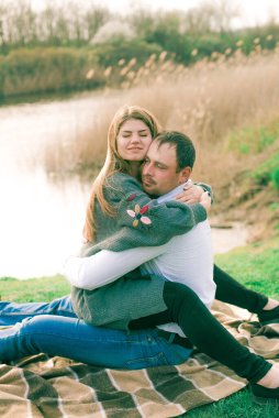 Bir çift uzun boylu genç adam ve uzun sarı saçlı kız arkadaşı nehir kıyısında şehrin dışında yürüyorlar. Duygular ve duygular. Yaşam tarzı. Ülke havası