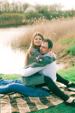 Bir çift uzun boylu genç adam ve uzun sarı saçlı kız arkadaşı nehir kıyısında şehrin dışında yürüyorlar. Duygular ve duygular. Yaşam tarzı. Ülke havası