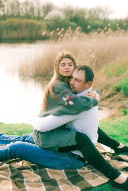 Bir çift uzun boylu genç adam ve uzun sarı saçlı kız arkadaşı nehir kıyısında şehrin dışında yürüyorlar. Duygular ve duygular. Yaşam tarzı. Ülke havası