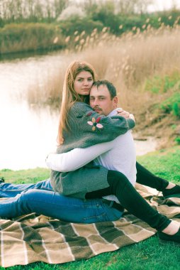 Bir çift uzun boylu genç adam ve uzun sarı saçlı kız arkadaşı nehir kıyısında şehrin dışında yürüyorlar. Duygular ve duygular. Yaşam tarzı. Ülke havası