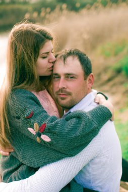 Bir çift uzun boylu genç adam ve uzun sarı saçlı kız arkadaşı nehir kıyısında şehrin dışında yürüyorlar. Duygular ve duygular. Yaşam tarzı. Ülke havası