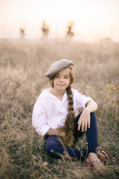 在夏日的田野里 一个漂亮的小女孩 金发碧眼 身穿白衬衫 头戴一顶男士的老式礼帽 — 图库照片