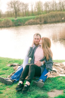 Bir çift uzun boylu genç adam ve uzun sarı saçlı kız arkadaşı nehir kıyısında şehrin dışında yürüyorlar. Duygular ve duygular. Yaşam tarzı. Ülke havası