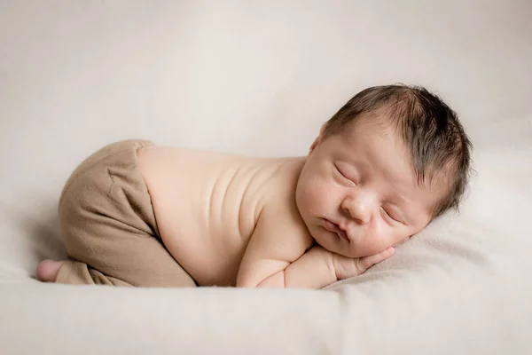 可愛いパンツに身を包んだ可愛い赤ちゃんがベージュのテキスタイルベッドスプレッドで寝ています 健康と母性 — ストック写真