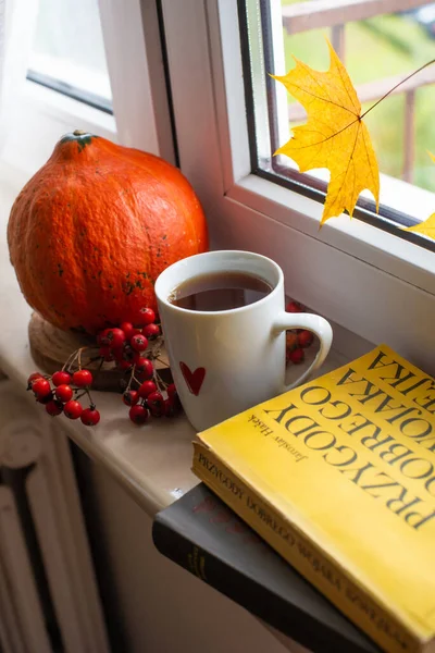 窓のティーカップ本黄色のカエデの葉とカボチャ 秋の気分 秋の家庭の快適 — ストック写真